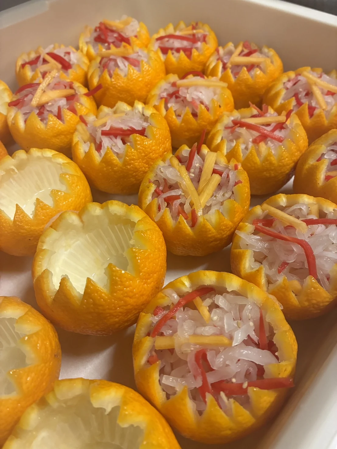 飾り切りした柚子に紅白の料理を盛り付けた仕込み風景